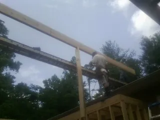 Carpenter setting a ridge beam over a new addition frame — Ice Dam Removal by Roofing Brothers in Denton